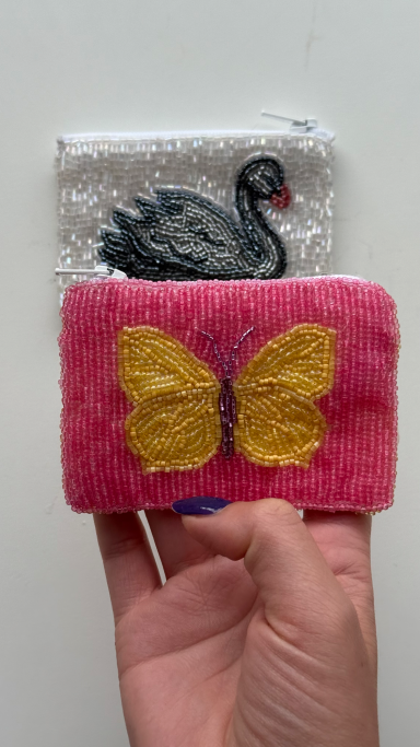 Hand hält zwei bunte Karten, eine mit schwarzem Schwan und die andere mit gelber Schmetterling.